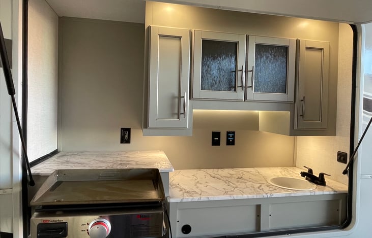 Outdoor kitchen with small propane flat griddle.  The kitchen has a sink with hot and cold water as well!