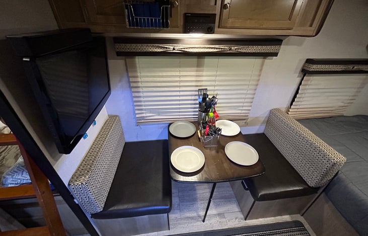 Table and benches that converts to single bed. Television, sound bar, DVD player, includes: paper plates and bowls, plastic cutlery, metal cutlery, cooking utensils, measuring cups, salt and pepper.