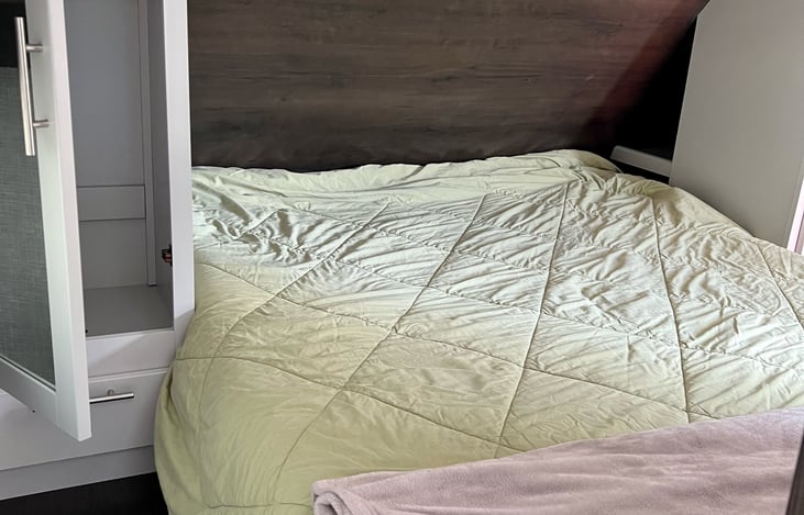 Master bed up front with a queen sized, comfortable mattress. Closet storage on both sides of bed, and storage on top. Bedding provided (minus pillows).