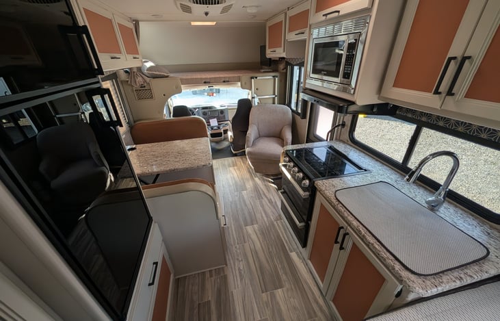 Bright, modern interior with a cute pop of color! Features a cozy rear queen bed, fully equipped kitchen, converting dinette, over-cab bunk, and an accent armchair. Clean, open, and ready for adventur