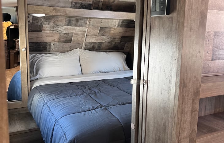 Storage space includes closets behind mirrors on either side of the bed with hangers and a shelf. Storage for bags and larger items under foot of the bed. Space to walk between bed and sliding doors.