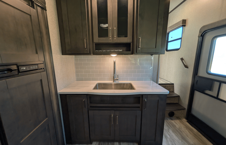Gourmet galley & rear den retreat! Includes a 12 cu ft fridge, pantry, stove/oven, dual sofas, theater seats, 50" TV, electric fireplace, and 3 slides for spacious high-end living.
