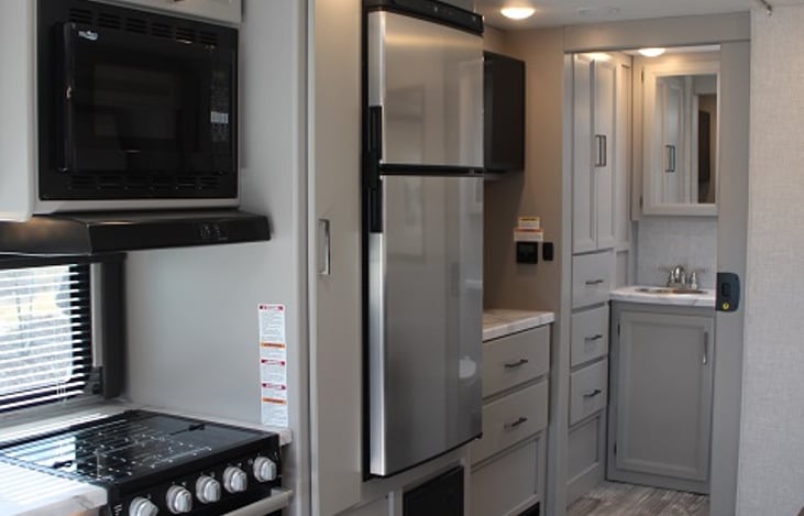 Convection microwave, three gas burners, and a great size refrigerator.  The bathroom has a shower, and a toilet, along with the sink and mirrors.  Towels are already provided.