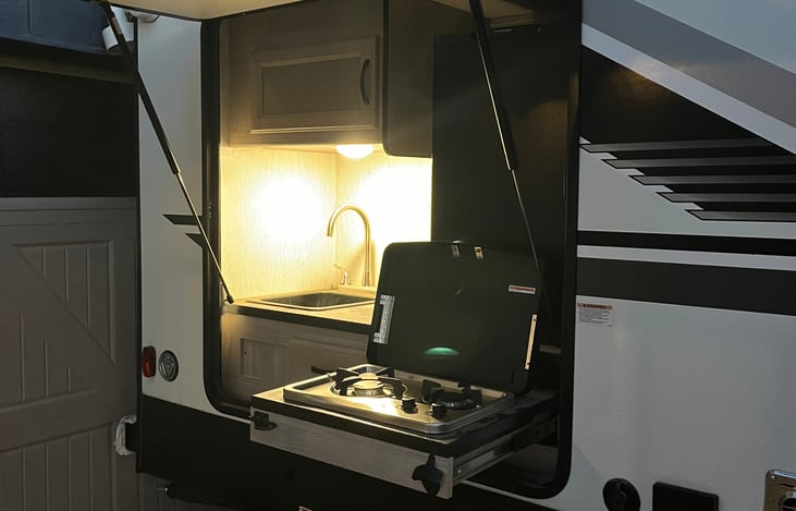 Outdoor kitchen with fridge two burner cook top and hot and cold stink with storage