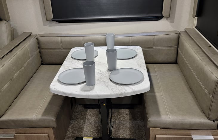 Padded dinette booth with blackout shades and tableware.