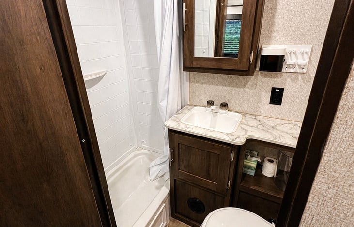 Clean, private bathroom with shower, sink, and storage