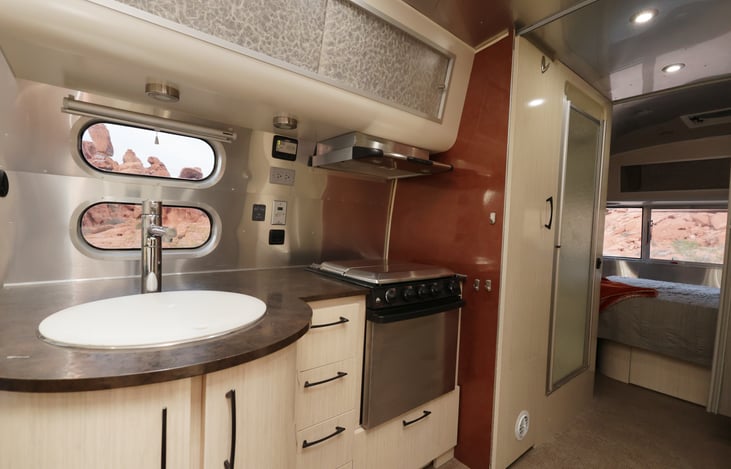 Kitchen with large 18" sink, three burner stove, oven, hood vent.