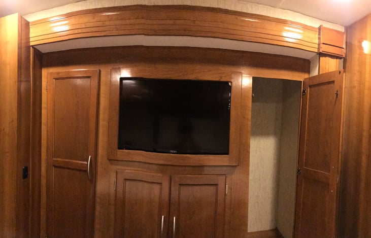 Bedroom closets and drawers below are surrounding the tv which has a cabinet behind it for even more storage.