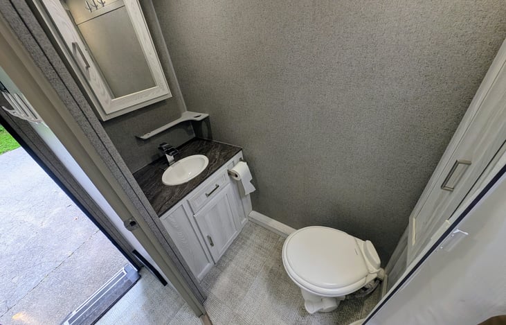 Convenient bathroom with ample storage, toilet and shower.
