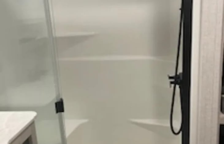 Roomy shower with shower seat and shelves.