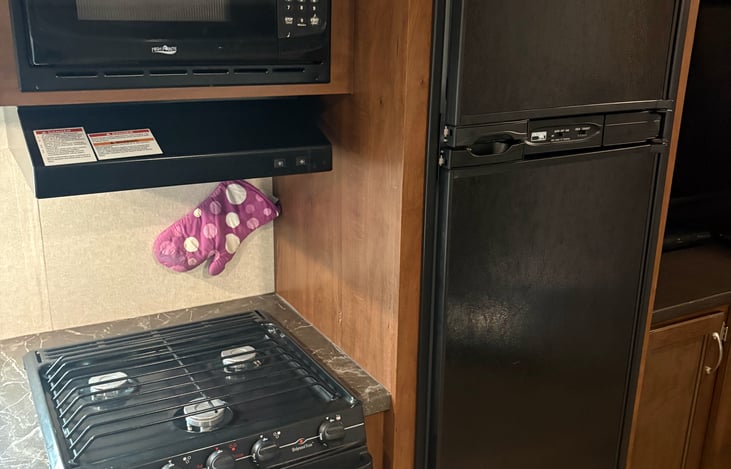 Freezer (on top), refrigerator (on bottom), 3 burner stove and fan, microwave