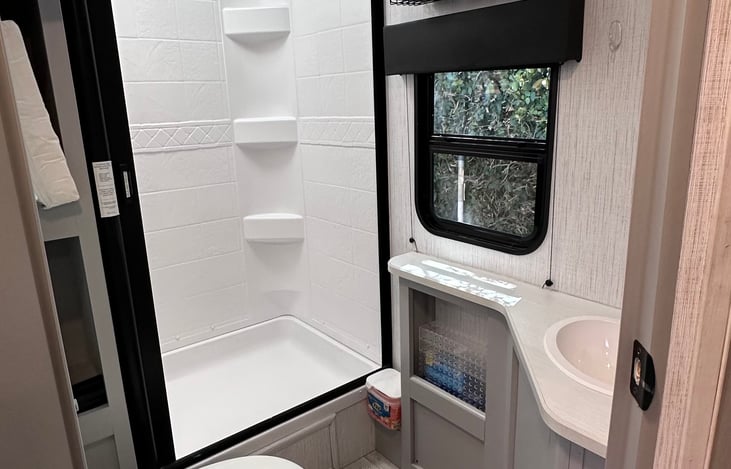 Bathroom: standup shower with handeld, sink, toiler and medicine cabinet. Three cubbies for storage.