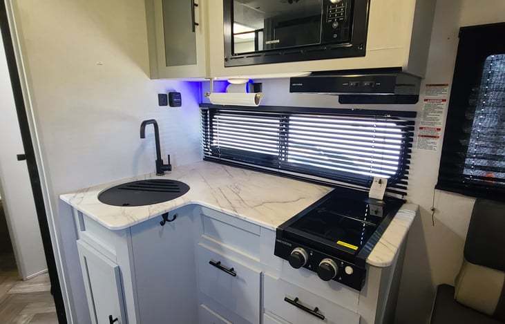 The kitchen will be equipped with some cleaning supplies. Two-burner gas stove with cover. USB charging station, microwave, utensils, cups, plates.