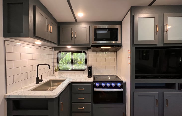 Meal prep in the stylish kitchen is a breeze with an oversized sink, under cabinet lighting, a three burner propane range and a microwave. A Nespresso OL espresso machine is provided for your use.