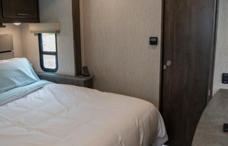 primary bedroom features barn doors to close off the bedroom completely and a bathroom door for complete privacy from the rest of the coach.