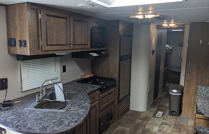 Kitchen area with sink, 3 burner stove and fridge/freezer combo.
