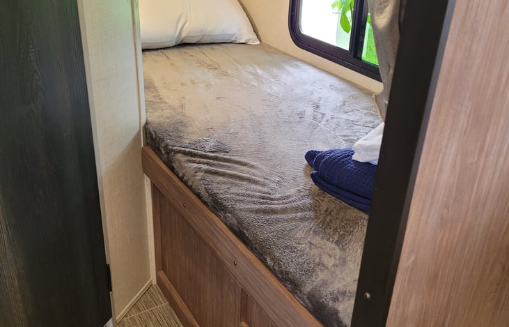 Bottom bunk with lamp and 12v USB wall ports for charging electronics.