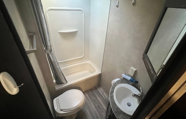 Spacious 3 piece bathroom - shower/tub, sink and mirror, and toilet.