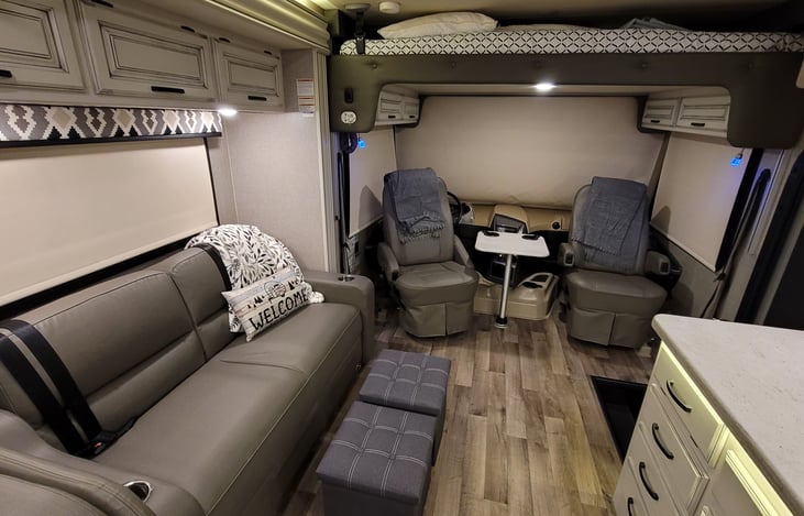 Entry to living area, setup with seats turned around and positioned with table setup in middle. Ottomans in place, blankets inside.