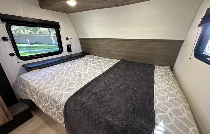 Queen bed sleeping area with front window and overhead storage.