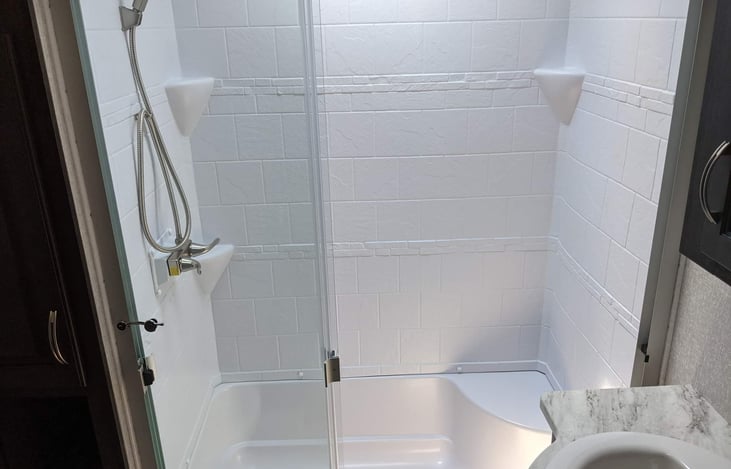 Walk-in shower and porcelain sink with mirror above and medicine cabinet storage. As well as under sink storage