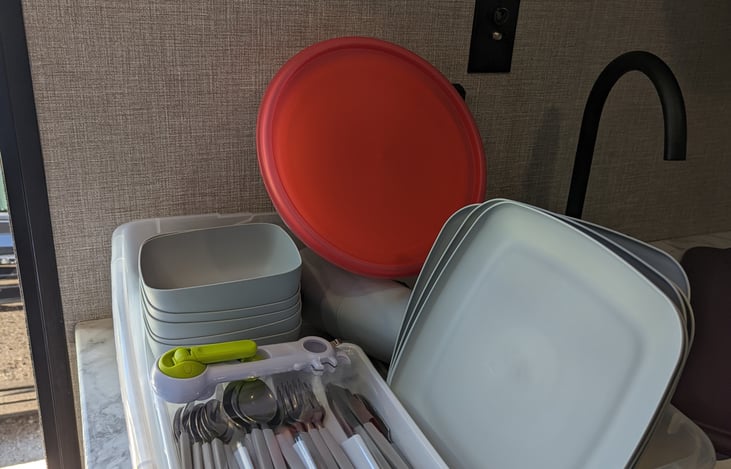 Plates, bowls, cups, silverware, can opener and mixing bowls.