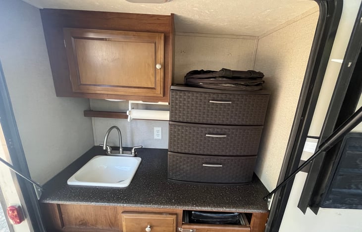 Outdoor kitchen sink and drawers stocked with plenty of paper plates and plastic wear