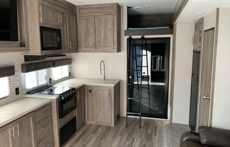 Glass door (locking) separates the main living area from the cargo/garage space. Loft area above this door can sleep one person, accessed by ladder.