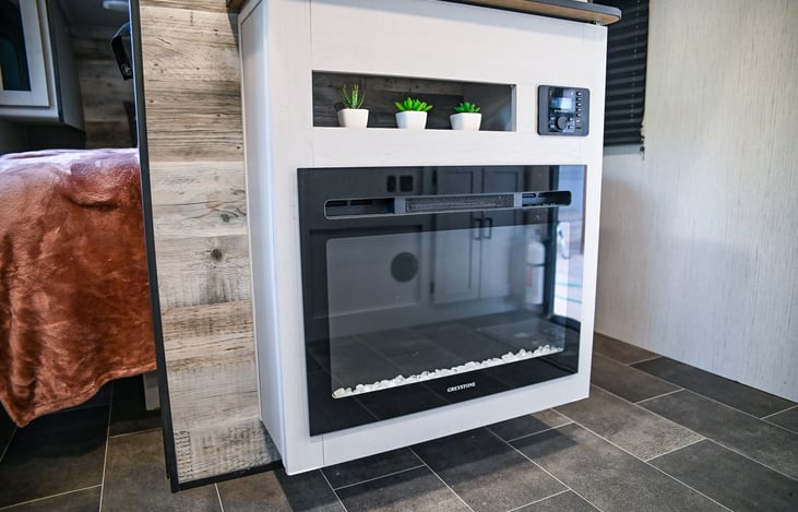 Cozy up by the beautiful fireplace, which not only adds a touch of elegance but also heats the travel trailer quickly, keeping you warm and comfortable on chilly nights.