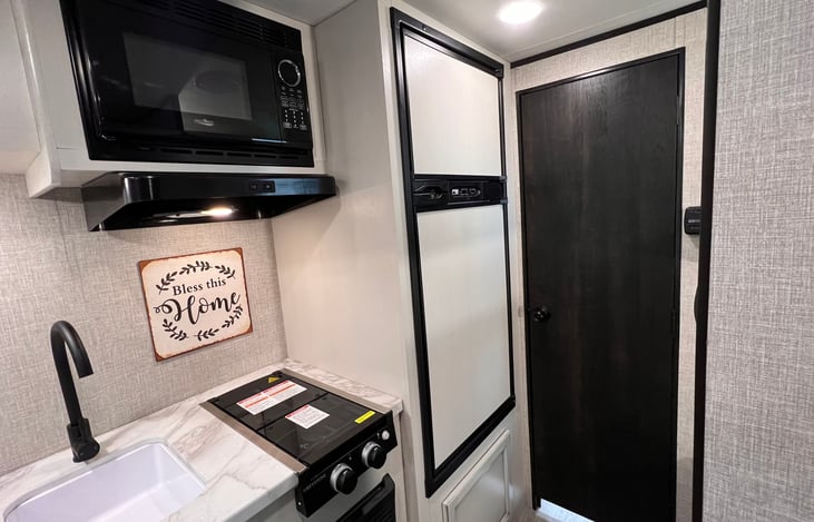 Microwave. Sink. Large fridge and freezer. Two burner stove with hood fan & light.