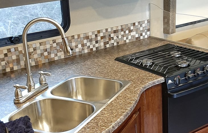 Galley fully stocked with plates, utensils, coffee maker, cutting board, Knifes. cooking pans. drink ware, towels, and cleaning supplies.