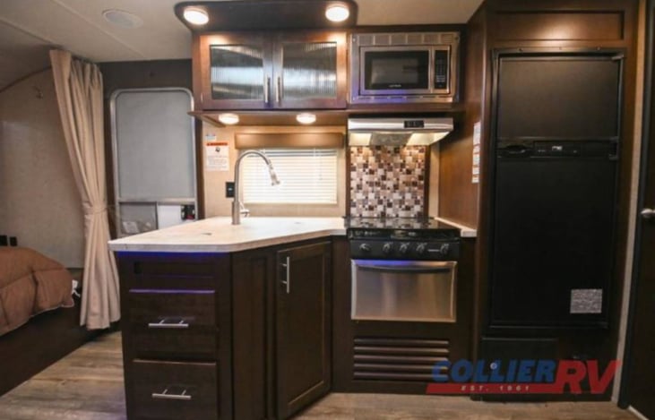 Main Cabin: View from Dinette slide out. Sink, Microwave, Fridge and Freezer,  3 burner stove with glass top for extra prep space /Oven
