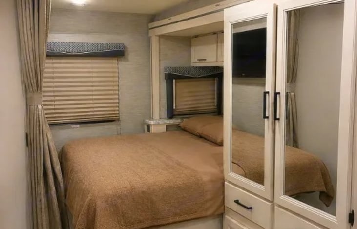 Features a 60" x 74" RV Queen bed. The mattress is designed with a folding seam so it can compact neatly when the slide-out is retracted, while remaining fully accessible when extended.