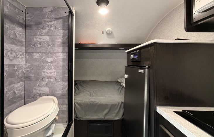 Full wet bath with toilet and shower, 12V fridge and freezer, camper queen bed.
