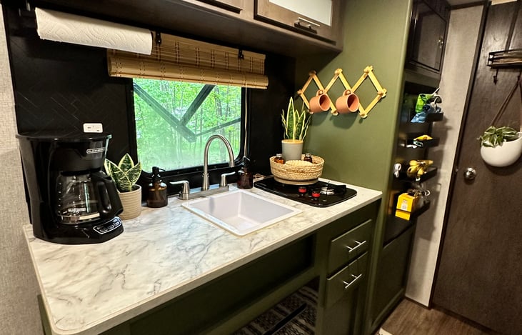 The kitchenette in our RV for rent not only features a two-burner propane cooktop but also includes a built-in electric fireplace. This unit supplies heat inside the RV on a cold night.