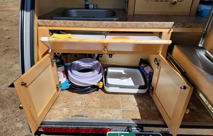 Under the sink. This is where you find the freshwater hose, foldable sink for cleaning dishes, and the battery.  There are other items under here as well.