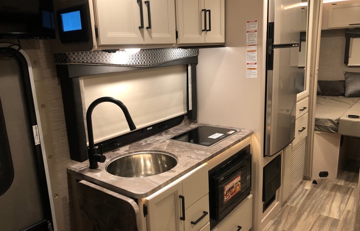 Full Kitchen equipped with stainless steel sink, two burner cooktop, and conviction oven and microwave