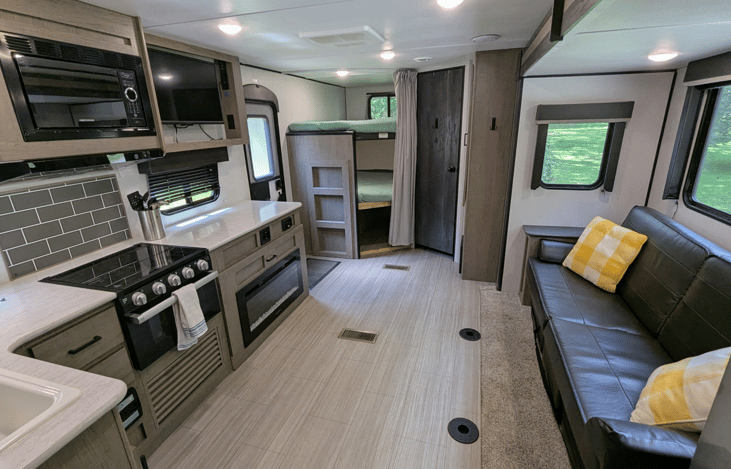 Spacious and cozy interior with well-equipped kitchen, large refrigerator, ample counter space, electric fireplace, TV, stereo, and bunks.