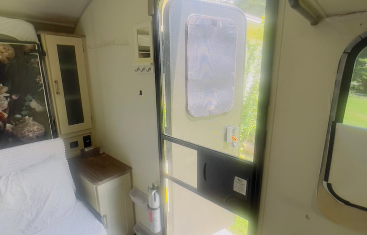 Door features a keypad lock and a blackout shade. key hook on wall next to the door.