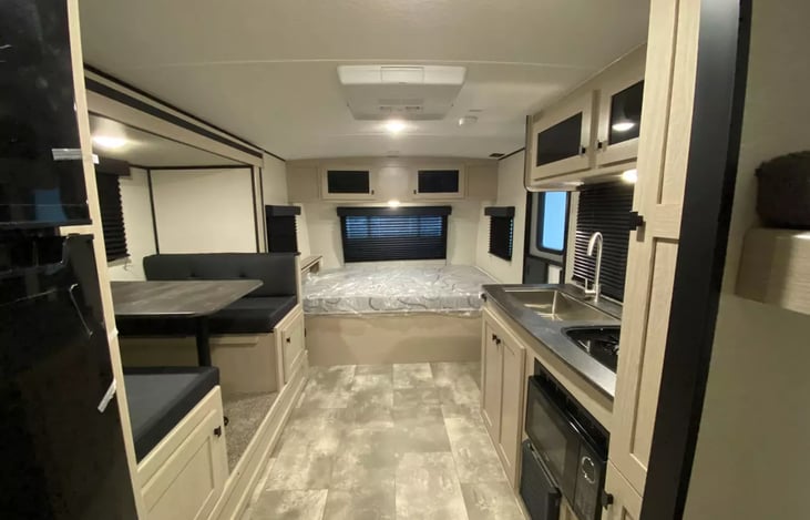 Rear to front view of unit interior with bedroom in front.  Comfortable queen mattress with ample storage above bed.  Electrical outlet & USB available for charging phones on the headboard.