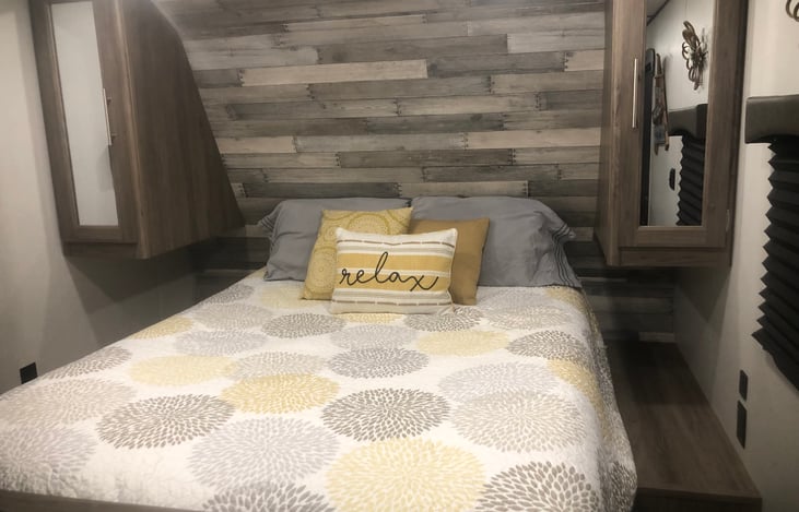 Master queen size walk around bed with privacy curtains separating the bedroom and living quarters