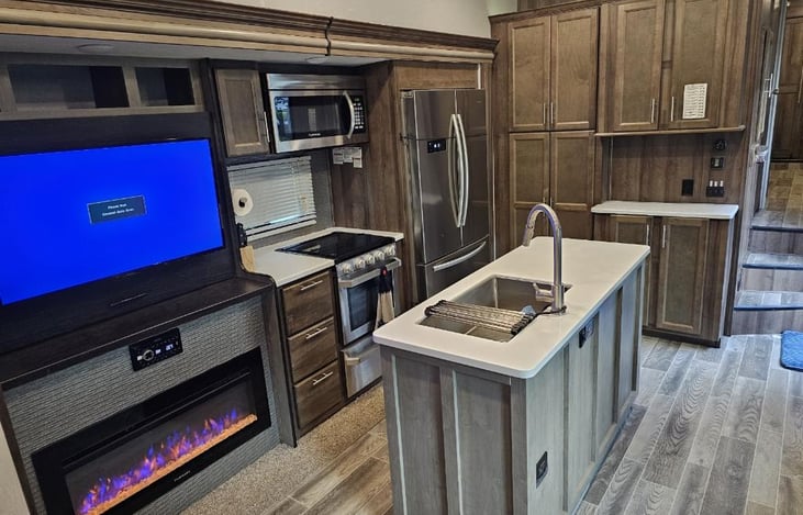 Kitchen Island with residential fridge, microwave, oven, and stove with plenty of cabinet storage