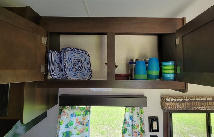 Overhead kitchen cabinet with dishware and cups.