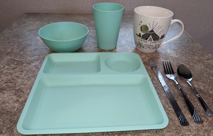 8 plates, bowls, cups, butter knives, forks, and spoons included. 4 coffee mugs. Not pictured: pots, pans, mixing bowls, tea kettle, cutting boards, stove top griddle, and more.