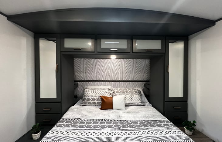 The primary bedroom is appointed with a queen sized bed, cozy bedding, reading lamps and plenty of storage!