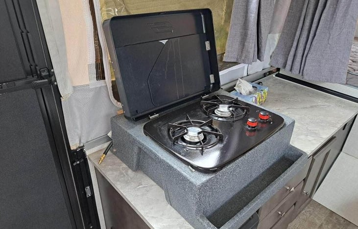 Two-burner propane stove. You can remove the two-burner stove from inside the camper and install it onto the mounting bracket located on the front outside of the camper.