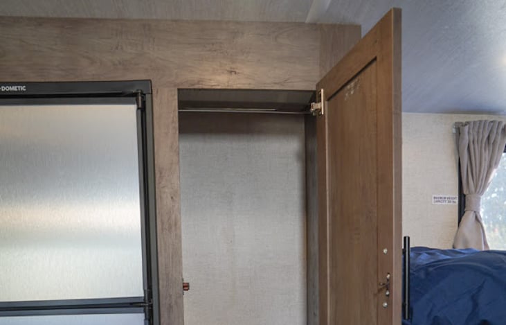 wardrobe includes plenty of hangers, a basket for storage, a step stool, and plenty of storage for food or personal items.