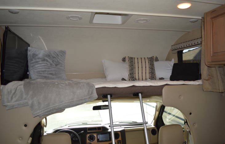 Cozy bunk above cab with a TV.
