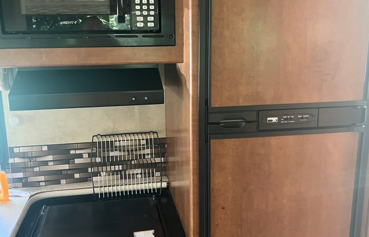 Microwave, three-burner stove, range hood, freezer, and refrigerator.