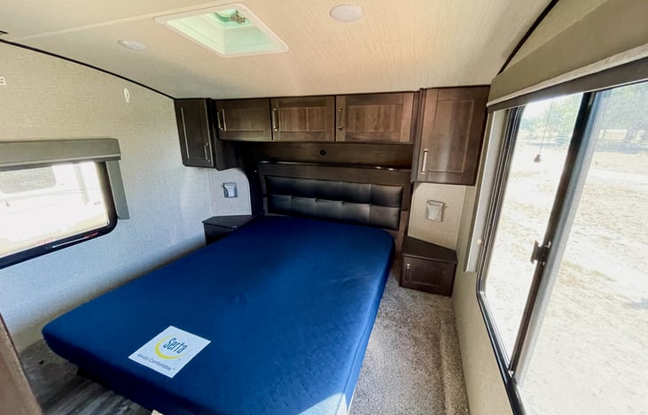 Master bedroom including a queen bed with storage underneath as well as closet and dresser drawers.